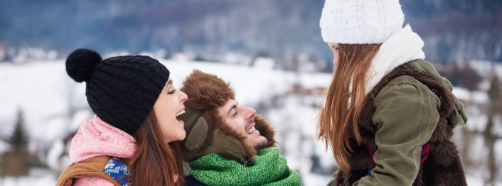 Three people in winter clothing enjoying a snowy landscape