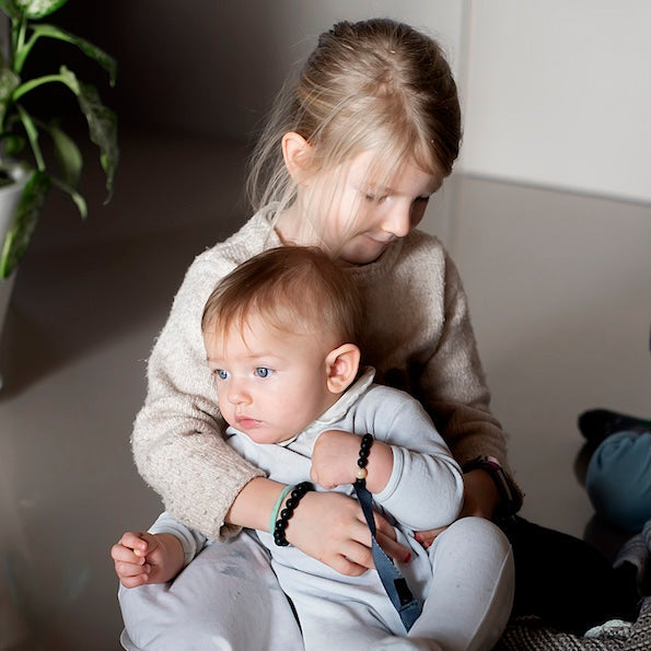 Two children sitting on a floor, one holding a toy.